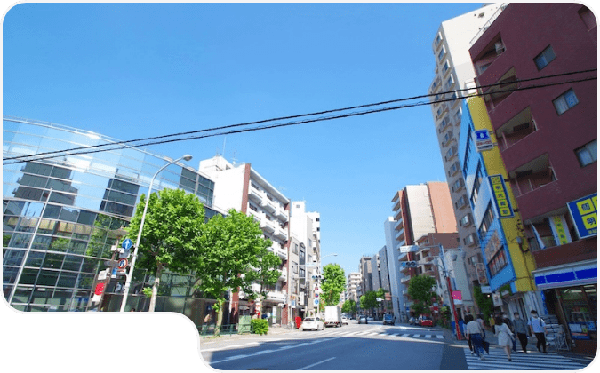 高層ビルや商業施設が並ぶ晴天の都市の大通りの風景